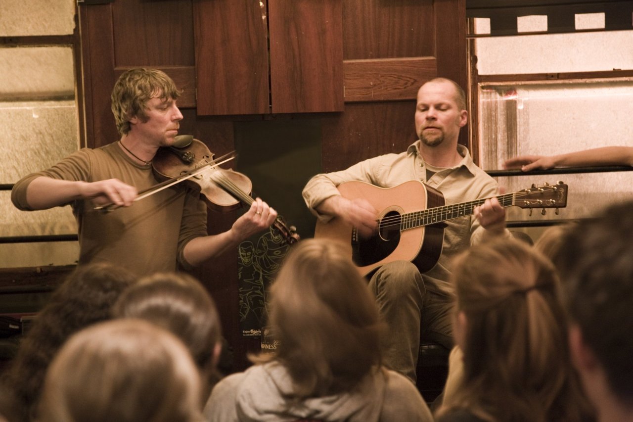 two men playing guitar and fiddle